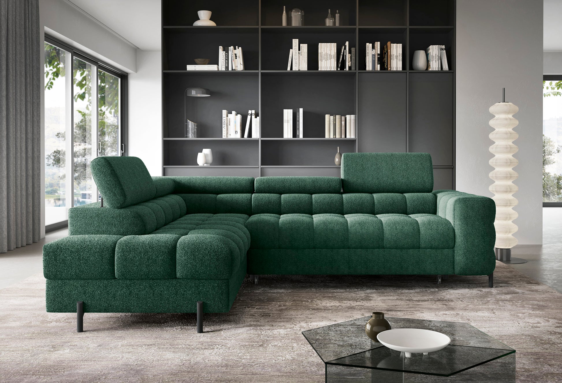 Zielony narożnik Ferucce lewy w tkaninie Amore 35, z pikowanym siedziskiem i regulowanymi zagłówkami, ustawiony we wnętrzu z regałem.