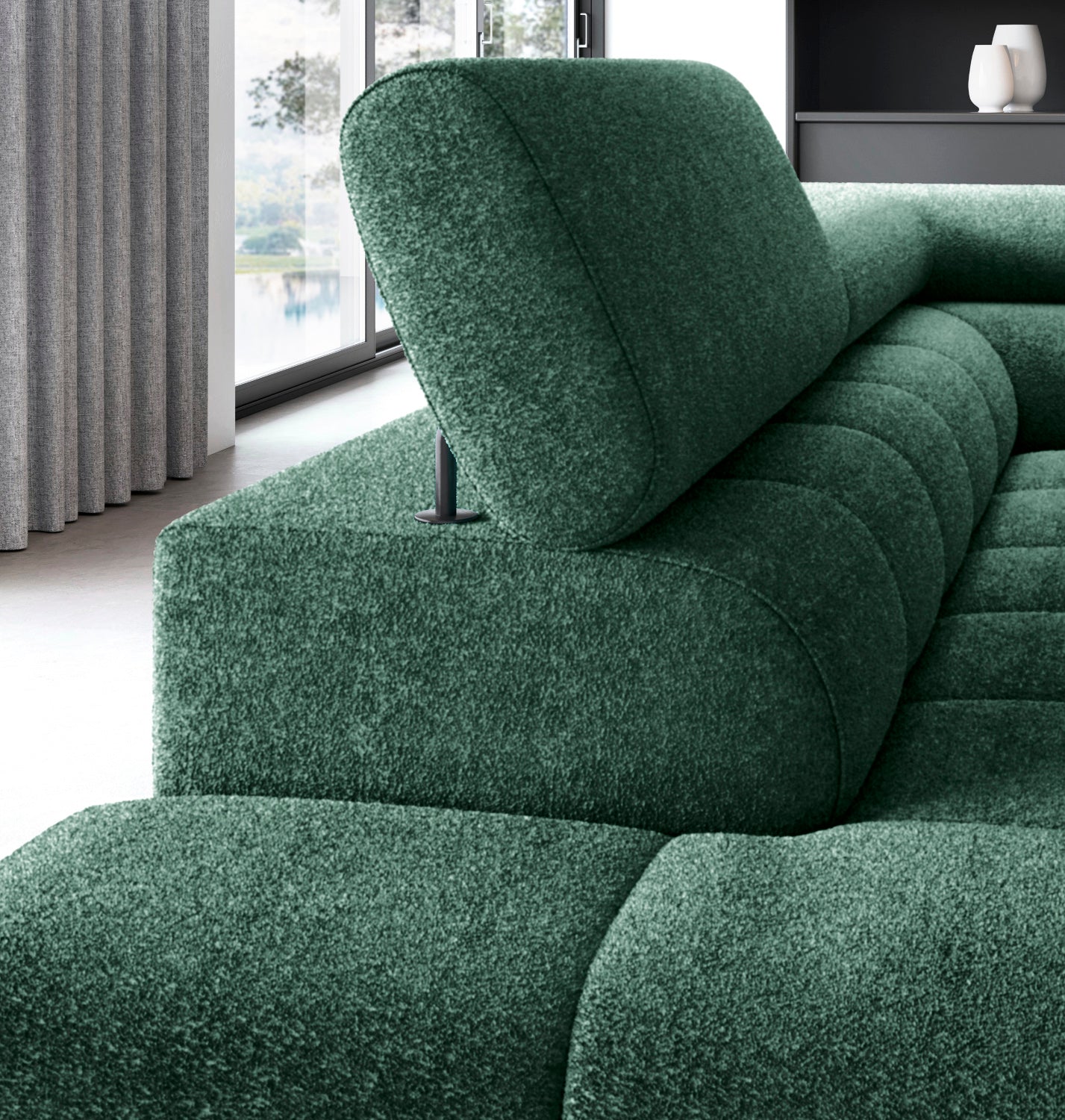 Zbliżenie na zagłówek narożnika Ferucce w tkaninie Amore 35 w kolorze ciemnozielonym, z widokiem na okno i zasłony w tle.