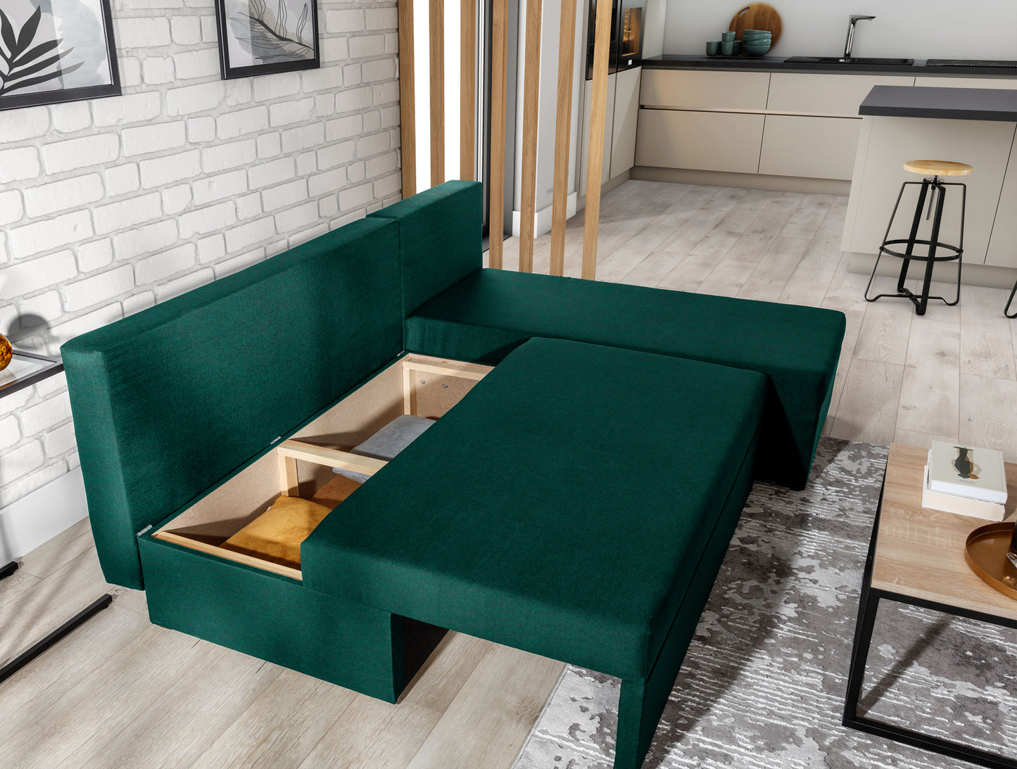 Narożnik Gino w kolorze Nube 35 zielony z otwartym pojemnikiem na pościel, ustawiony w jasnym, przestronnym wnętrzu.