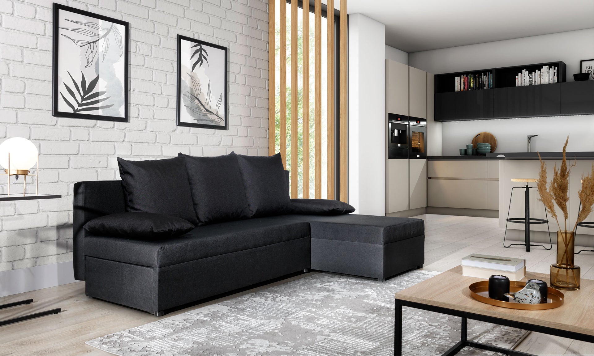 Narożnik Gino w kolorze Sawana 14 czarny, ustawiony w nowoczesnym salonie z białą ceglaną ścianą i jasną kuchnią w tle.