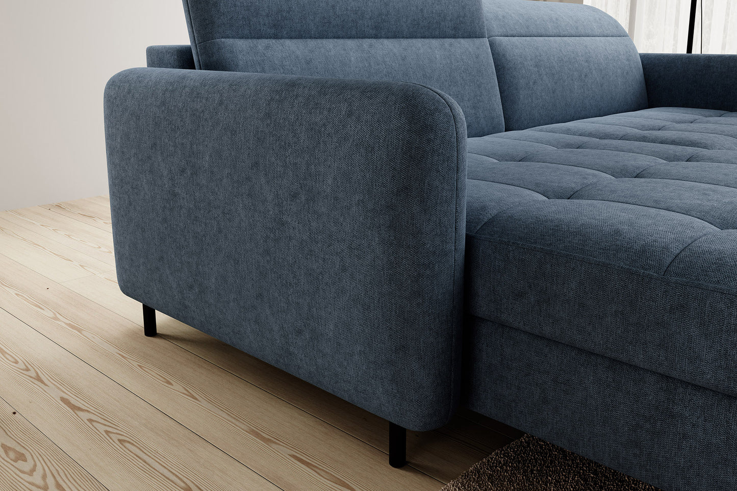 Detal zaokrąglonego podłokietnika narożnika Gomsi Raquel 40 niebieski w układzie lewym na tle jasnej drewnianej podłogi.