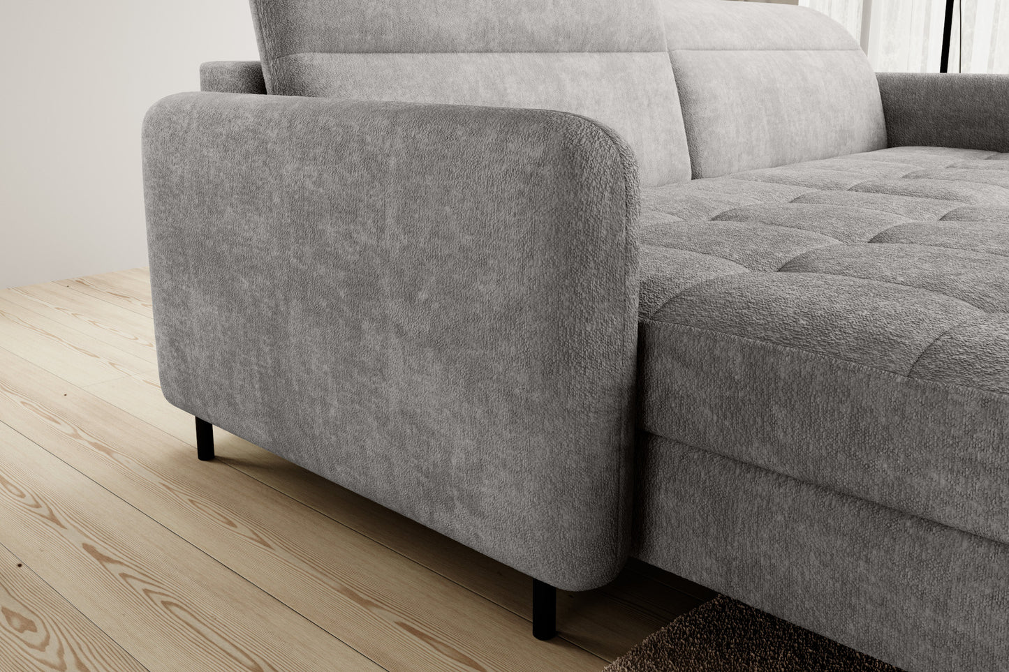 Detal zaokrąglonego podłokietnika narożnika Gomsi Raquel 03 jasnoszary w układzie lewym na tle jasnych zasłon i drewnianej podłogi.