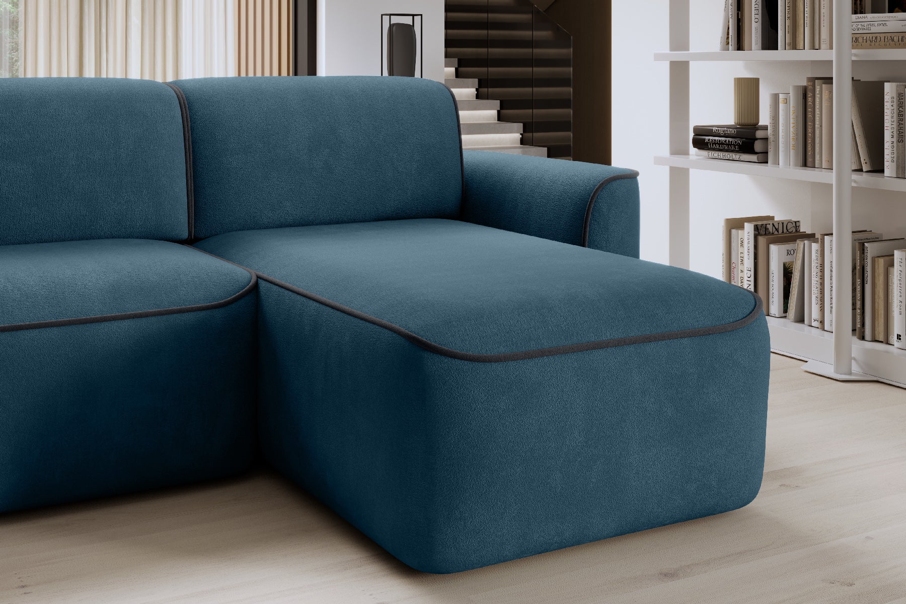 Zbliżenie na szezlong narożnika Ume w układzie prawym, tkanina Amore 40 granatowa z lamówką Velvetmat 06 ciemnoszarą, w tle regał z książkami.