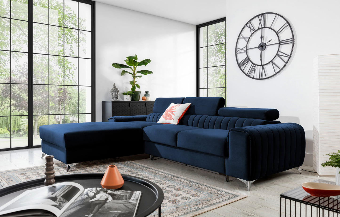 Narożnik Grayson Monolith 79 niebieski w aranżacji salonu z jasnymi dodatkami i dużymi oknami – stylowy układ lewy.