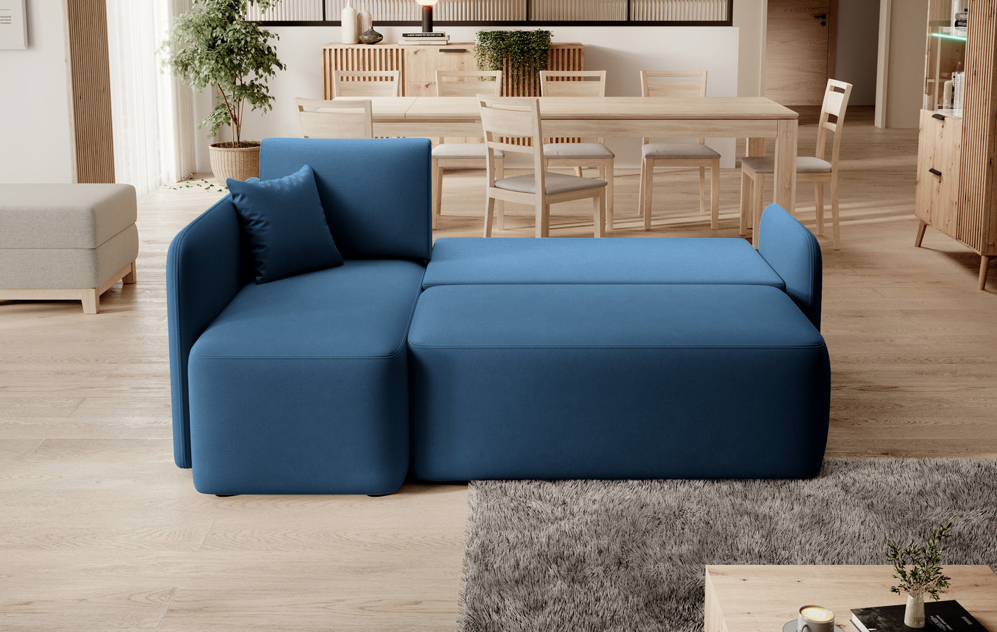 Tapicerowany narożnik z szezlongiem i poduszkami w stylu Home and Garden – granatowy akcent w jasnym wnętrzu.