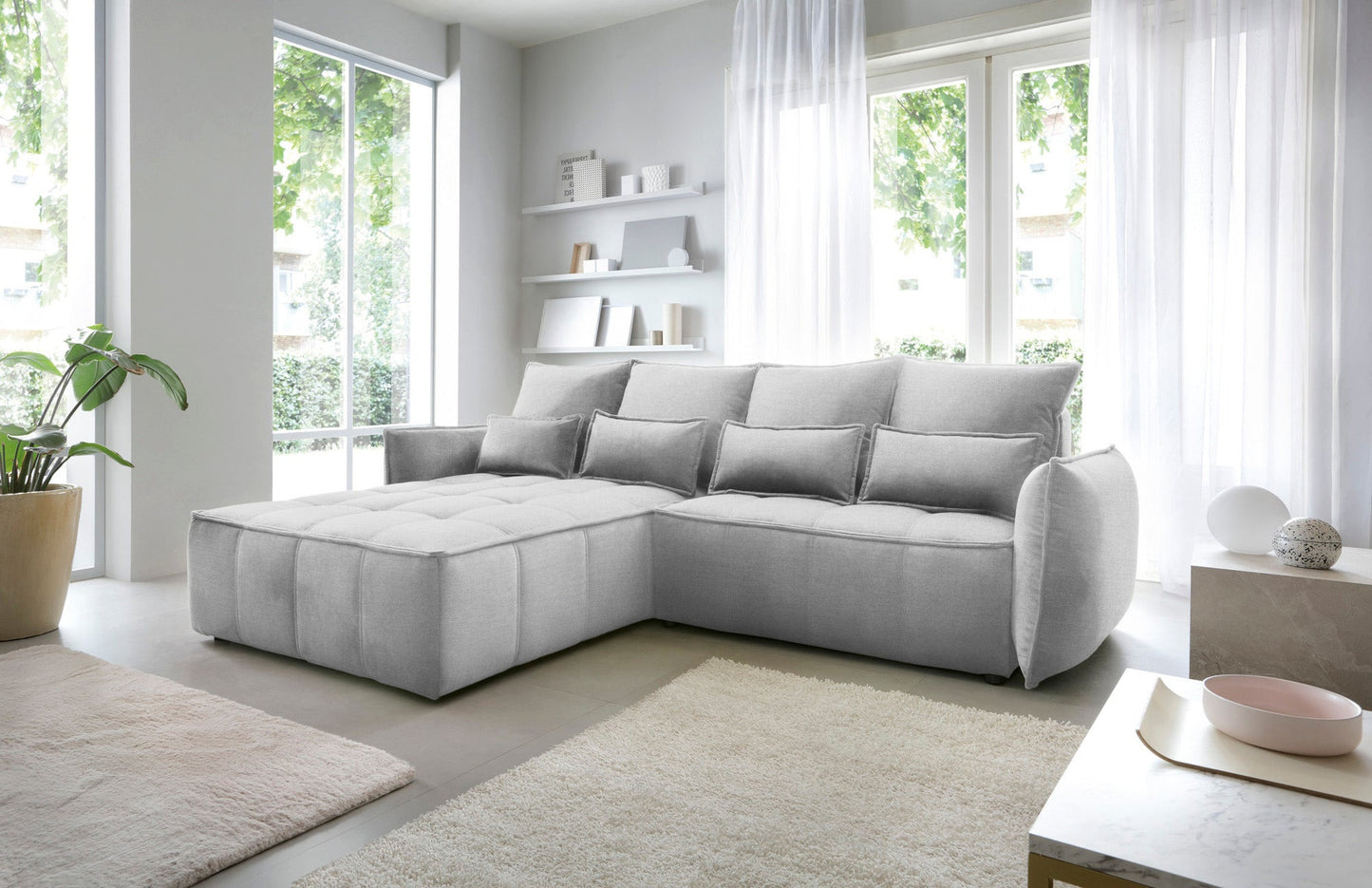 Narożnik Campo w układzie lewym, tapicerka Nube 03 jasnoszara, widok z boku w nowoczesnym wnętrzu z minimalistycznymi regałami.