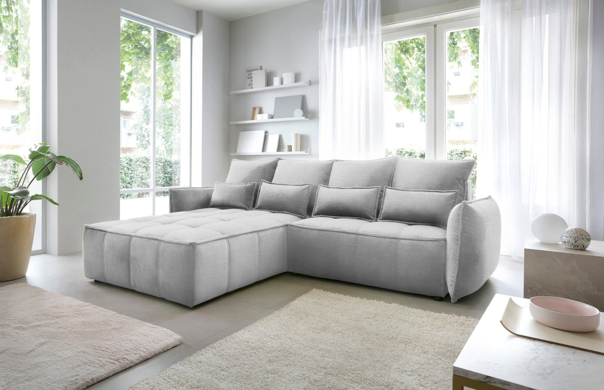 Narożnik Campo w układzie lewym, tapicerka Nube 03 jasnoszara, widok z boku w nowoczesnym wnętrzu z minimalistycznymi regałami.