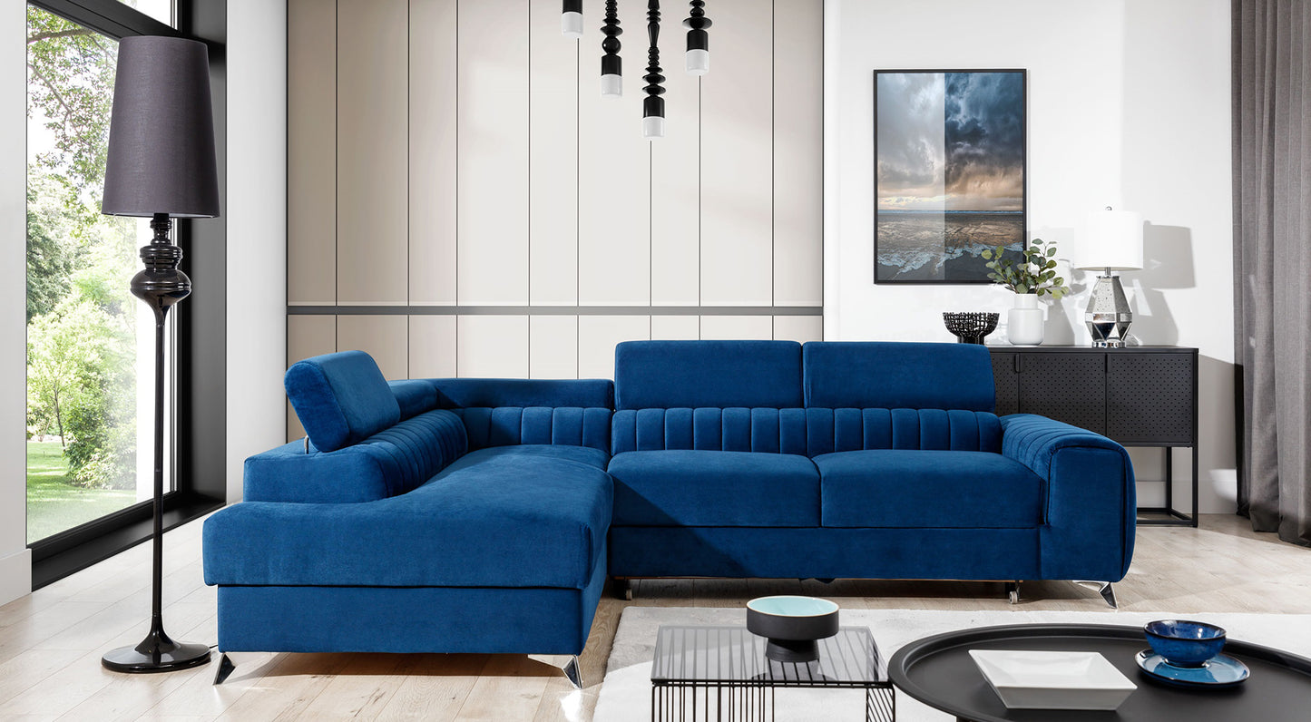 Narożnik Laurence w kolorze Kronos 09 granatowy, układ lewy, ustawiony w nowoczesnym salonie z dużymi oknami i jasnym wystrojem.