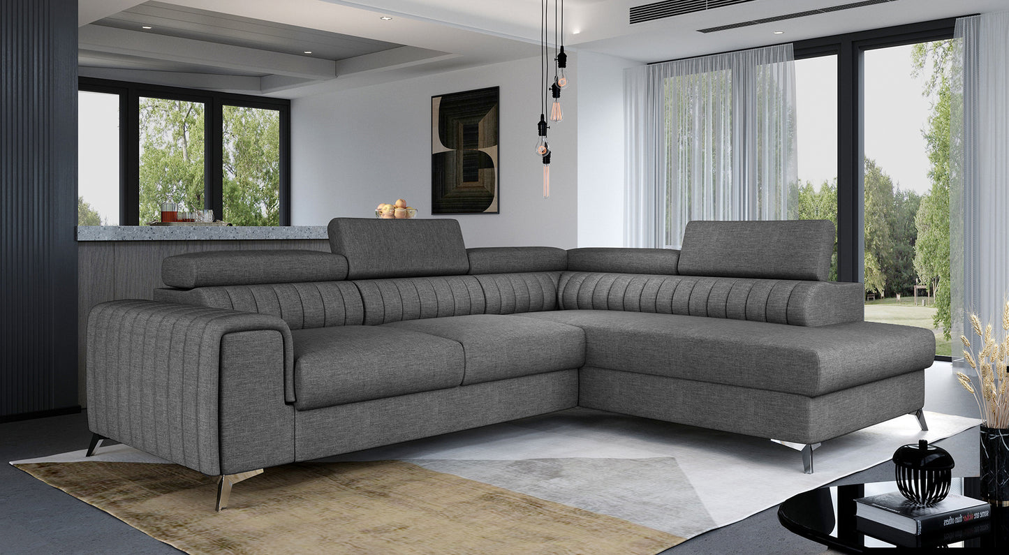 Narożnik Laurence w kolorze Sawana 05 ciemnoszary, układ prawy, ustawiony w przestronnym salonie z dużymi oknami i nowoczesnym wystrojem.