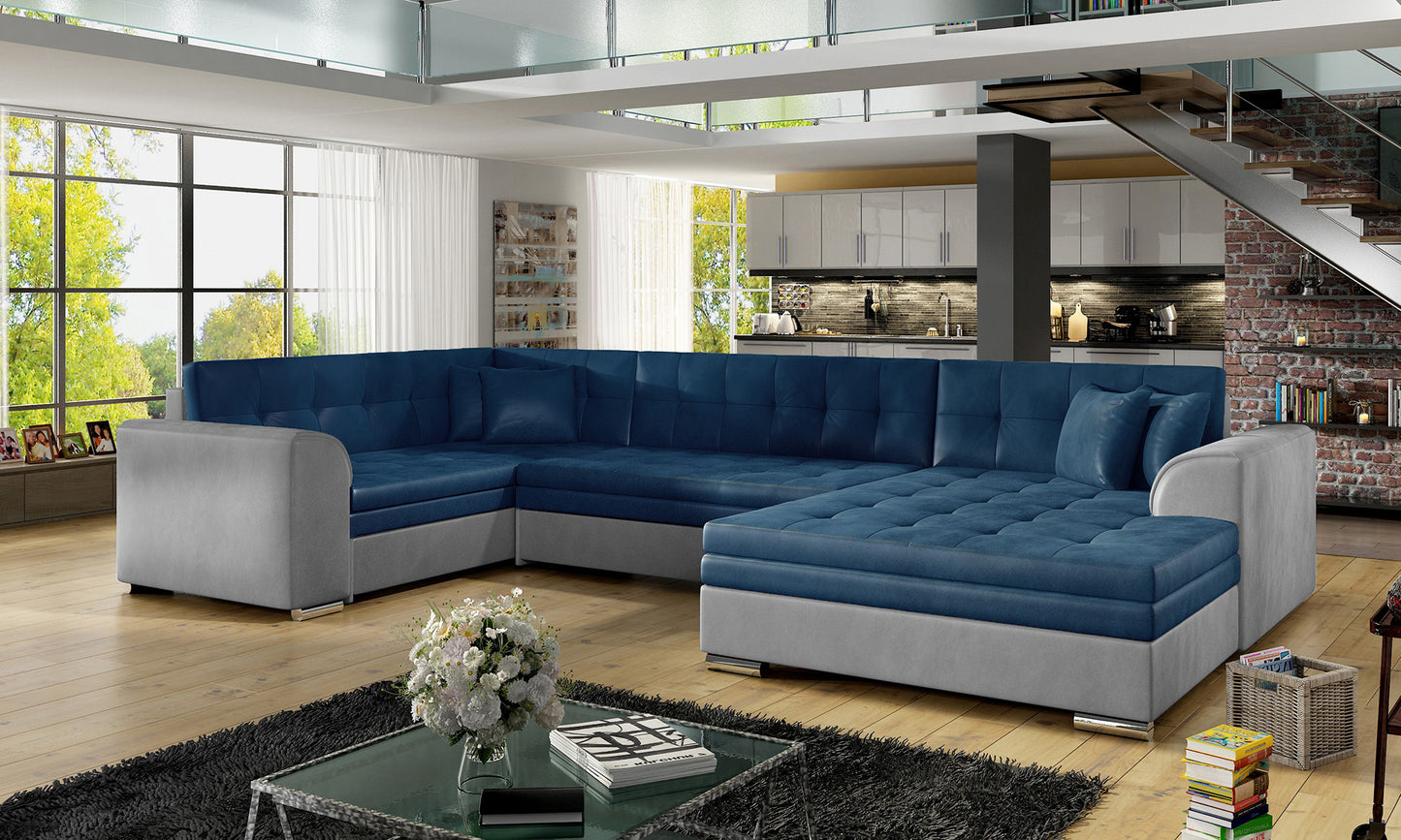 Narożnik Damario Monolith 77 niebieski / Monolith 84 jasnoszary ustawiony w nowoczesnym salonie z dużymi oknami i jasnym wystrojem wnętrza.