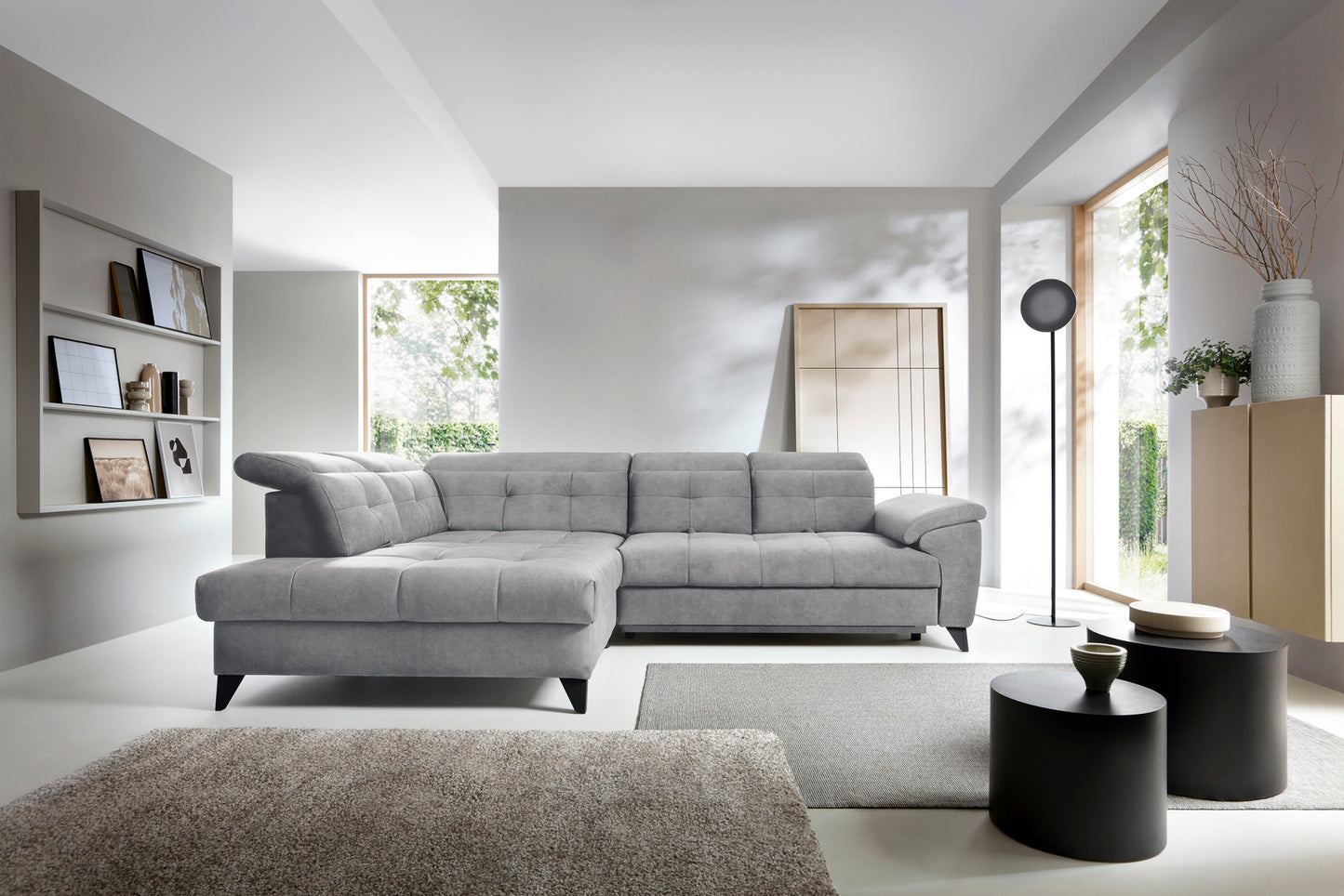 Narożnik Inferne Relax 04 szaro-brązowy w układzie lewym ustawiony w stylowym wnętrzu obok czarnych stolików i stojącej lampy przy dużym oknie.