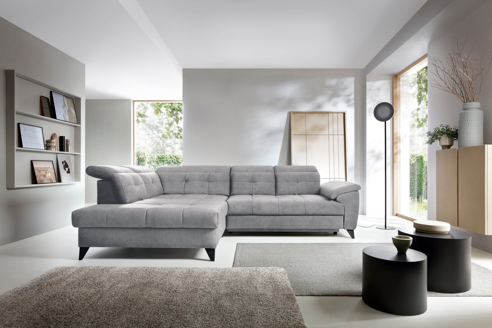 Narożnik Inferne Relax 04 szaro-brązowy w układzie lewym ustawiony w stylowym wnętrzu obok czarnych stolików i stojącej lampy przy dużym oknie.