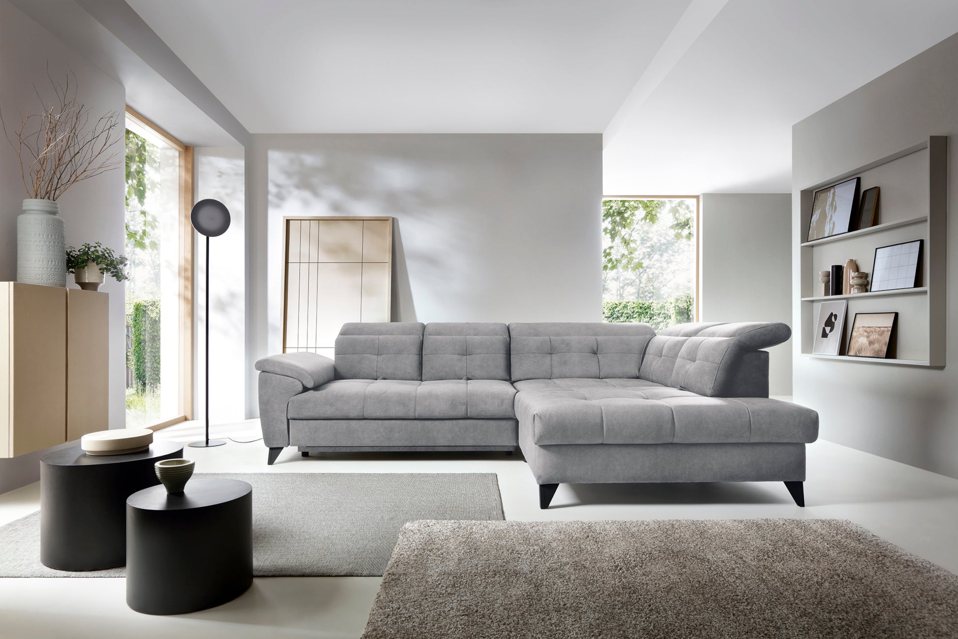 Narożnik Inferne Relax 04 szaro-brązowy w układzie prawym ustawiony w stylowym wnętrzu obok czarnych stolików i stojącej lampy przy dużym oknie.