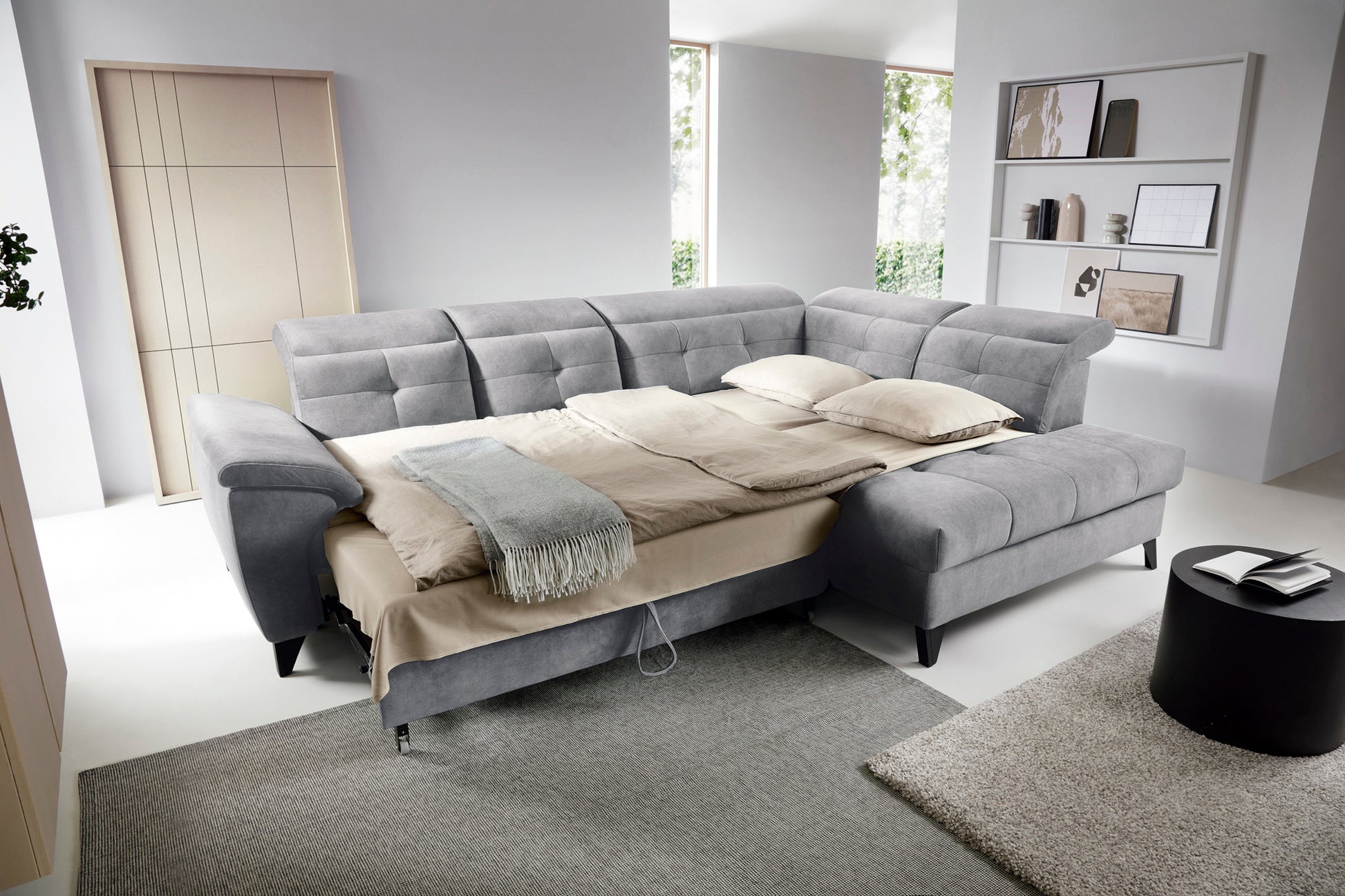 Narożnik Inferne Relax 04 szaro-brązowy w układzie prawym rozłożony jako łóżko, z oparciami odchylonymi w różnych pozycjach i pościelą na siedzisku.