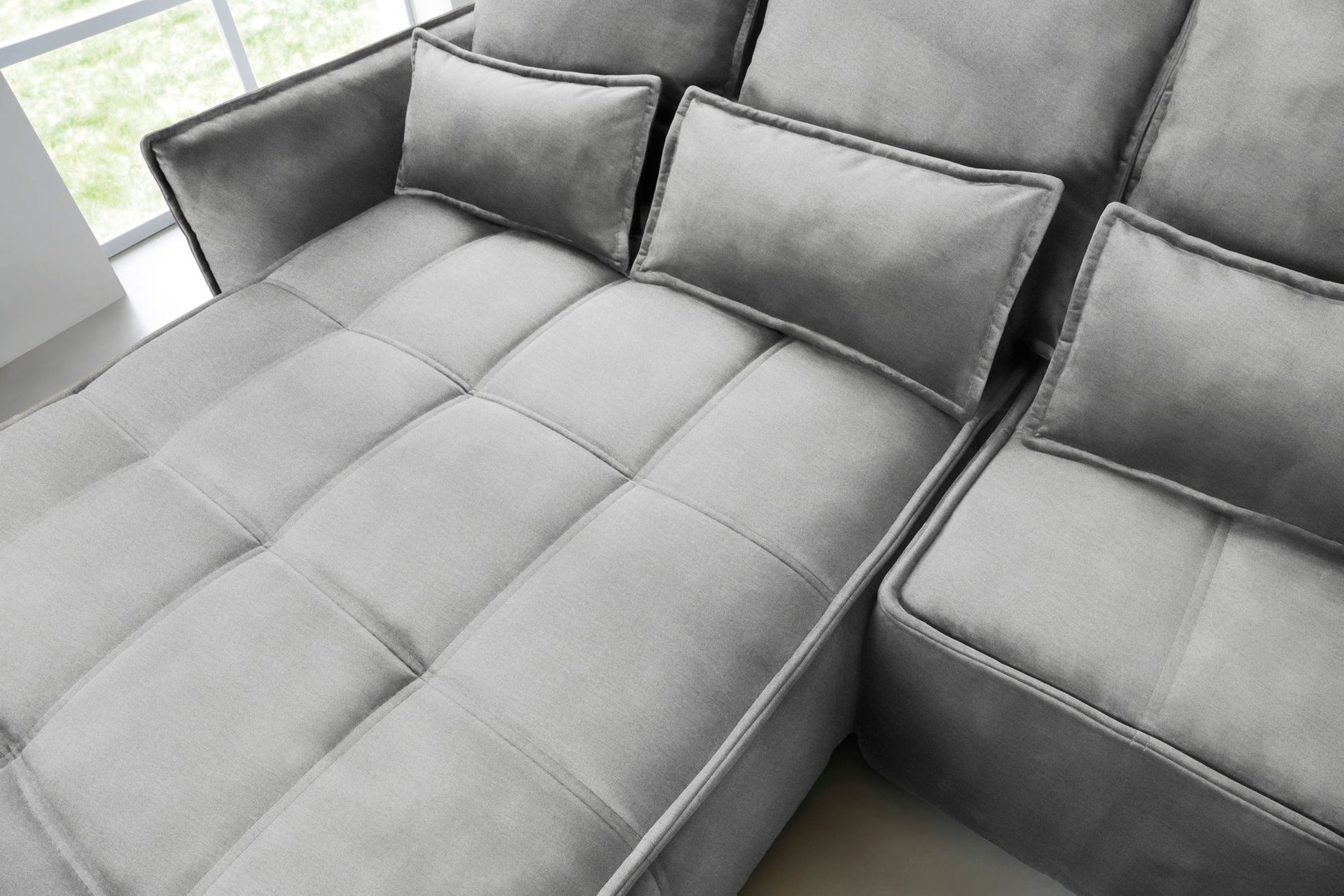 Zbliżenie na pikowane siedzisko i prostokątne poduszki narożnika Campo w układzie lewym, tkanina Nube 04 szary.