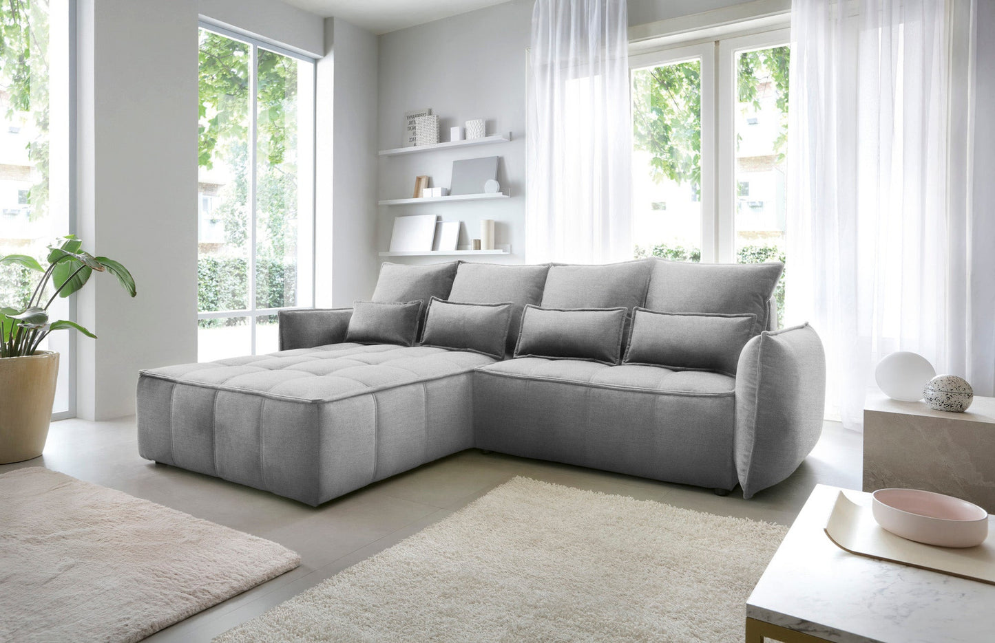 Narożnik Campo w układzie lewym, tapicerka Nube 04 szary, prezentowany w nowoczesnym wnętrzu z dywanem i minimalistycznymi półkami na ścianie.