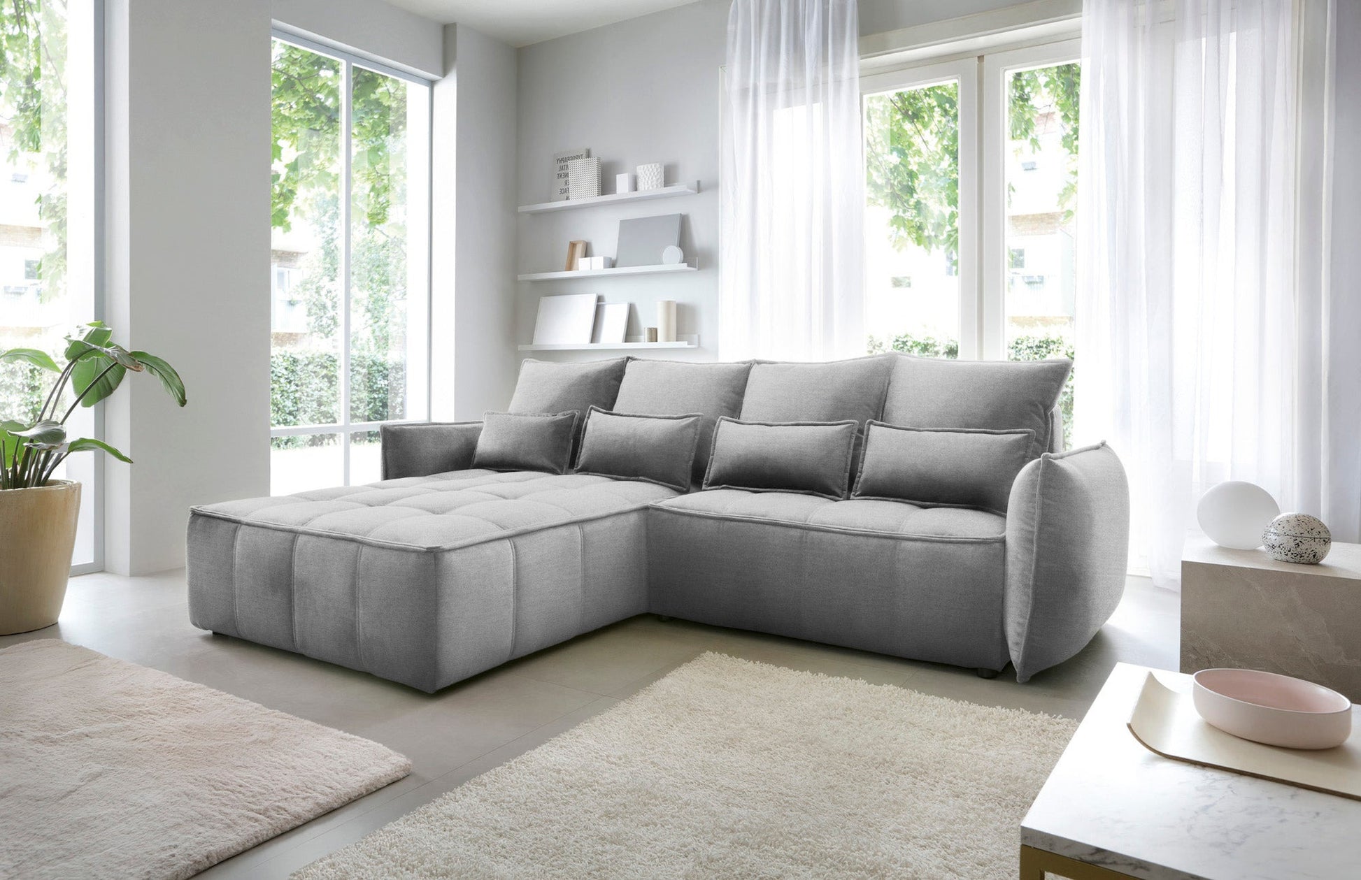 Narożnik Campo w układzie lewym, tapicerka Nube 04 szary, prezentowany w nowoczesnym wnętrzu z dywanem i minimalistycznymi półkami na ścianie.