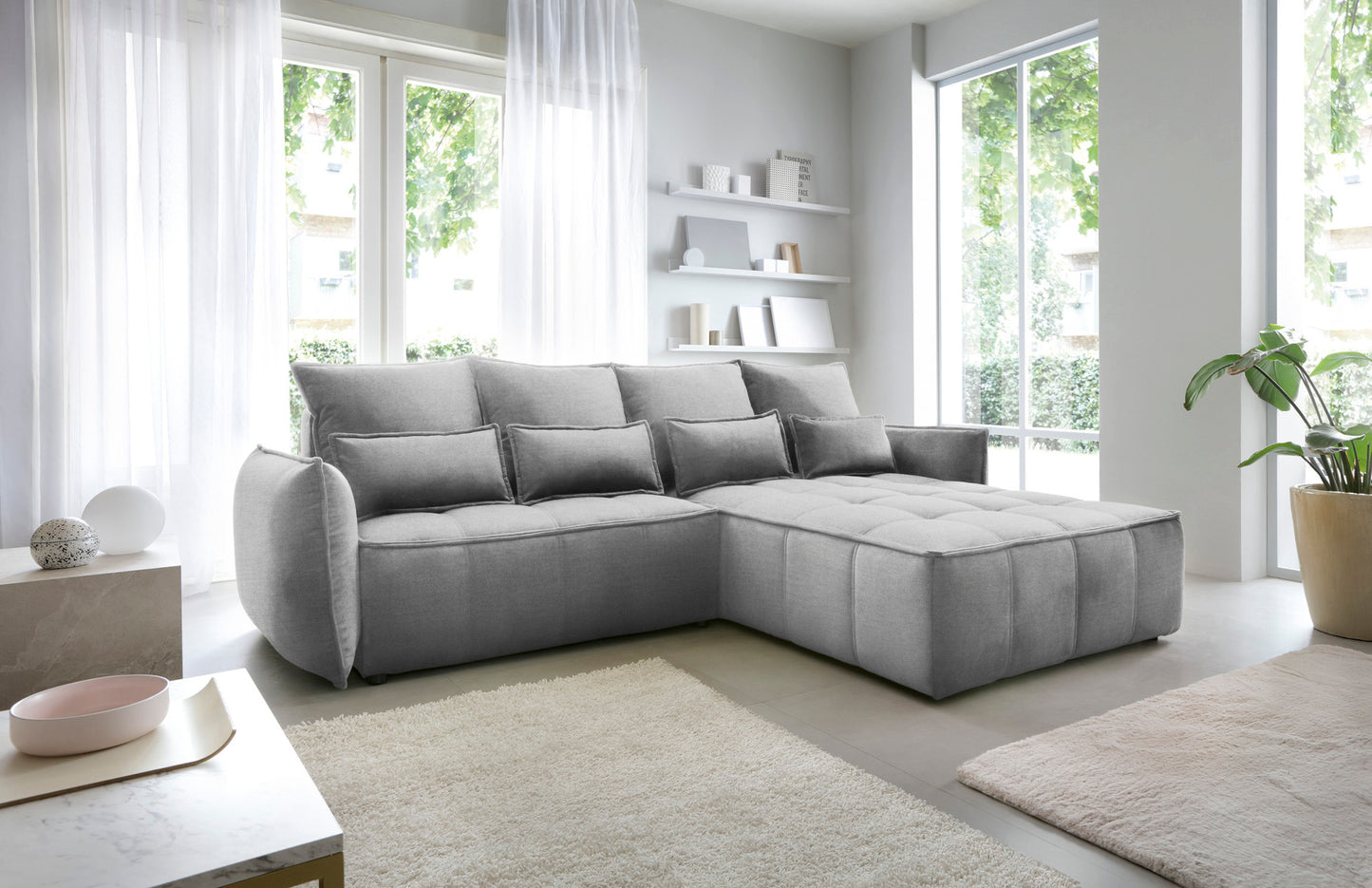 Narożnik Campo w układzie prawym, tapicerka Nube 04 szary, prezentowany w nowoczesnym wnętrzu z minimalistycznymi półkami i stolikiem kawowym.