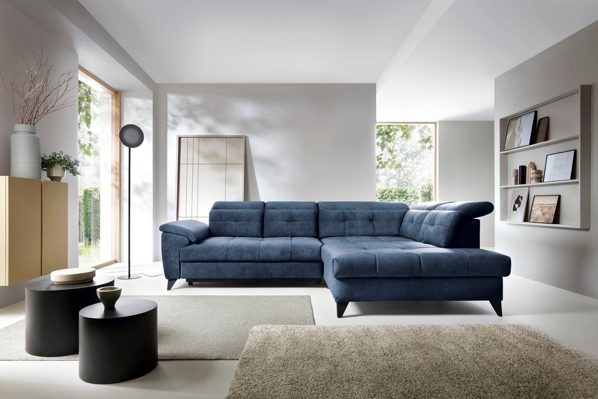Narożnik Inferne Aura 40 zgaszony niebieski w układzie prawym ustawiony w nowoczesnym salonie obok stolików kawowych i lampy stojącej.