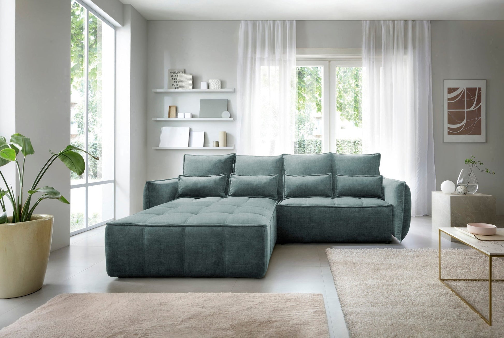 Narożnik Campo Manhattan 38 zielony w układzie lewym ustawiony w jasnym salonie przy dużym oknie, ozdobiony prostokątnymi poduszkami i antyczną lampą na stoliku.