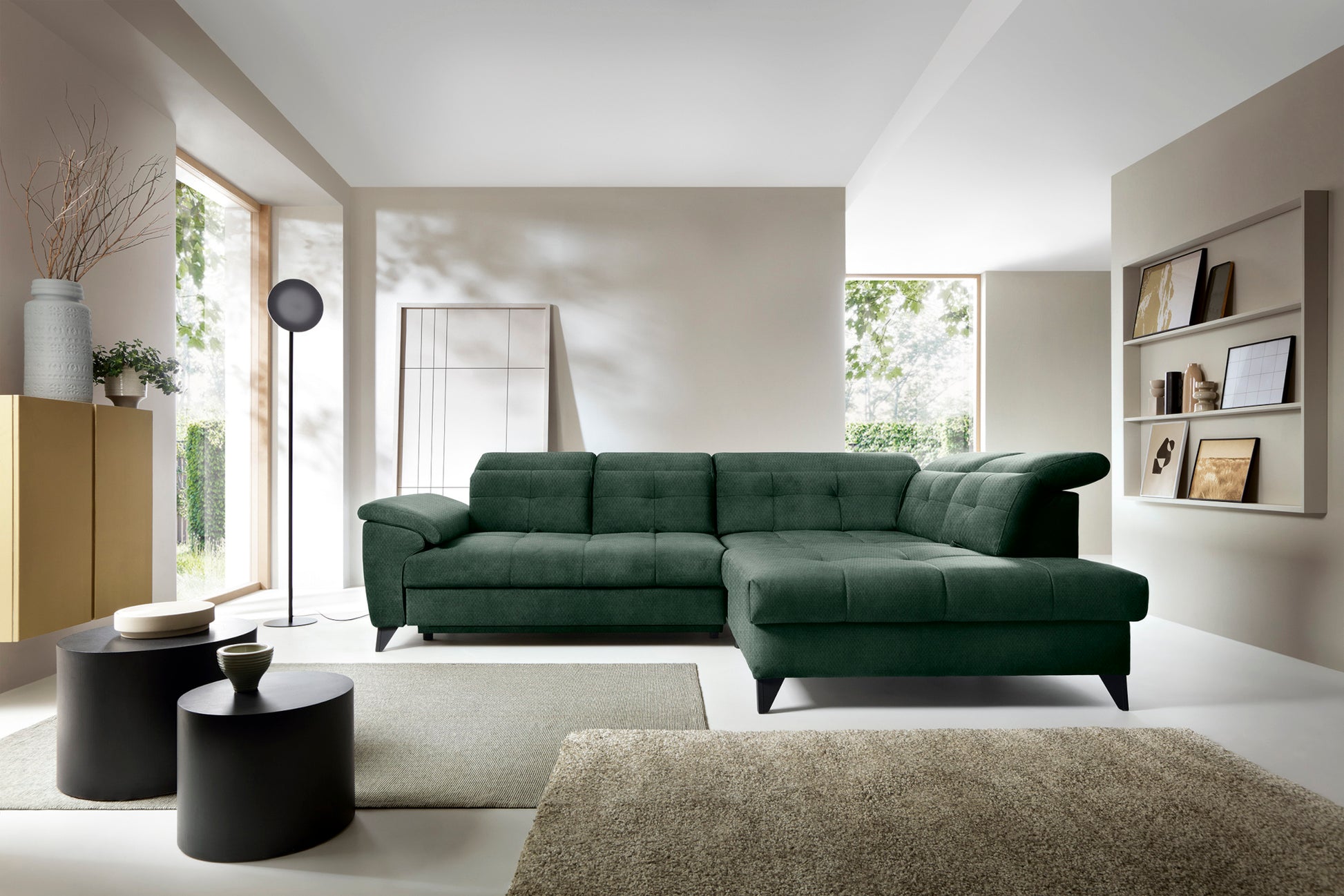 Narożnik Inferne Raquel 35 zielony w układzie prawym w nowoczesnym salonie przy czarnych stolikach i stojącej lampie.