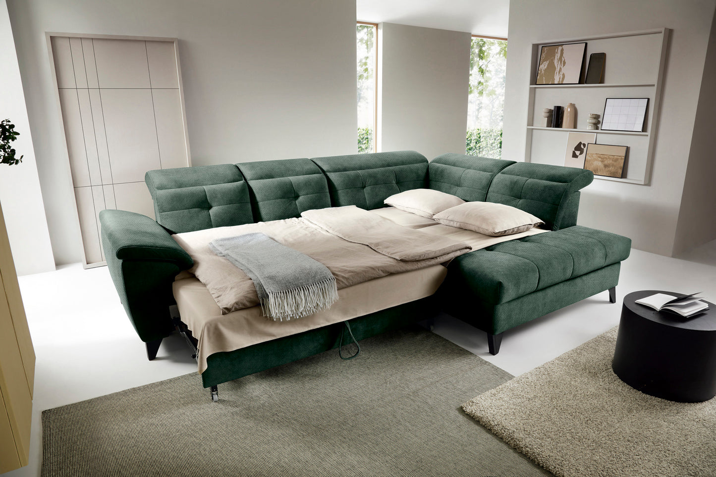 Narożnik Inferne Raquel 35 zielony w układzie prawym rozłożony jako łóżko, z pościelą i przestawionymi oparciami.