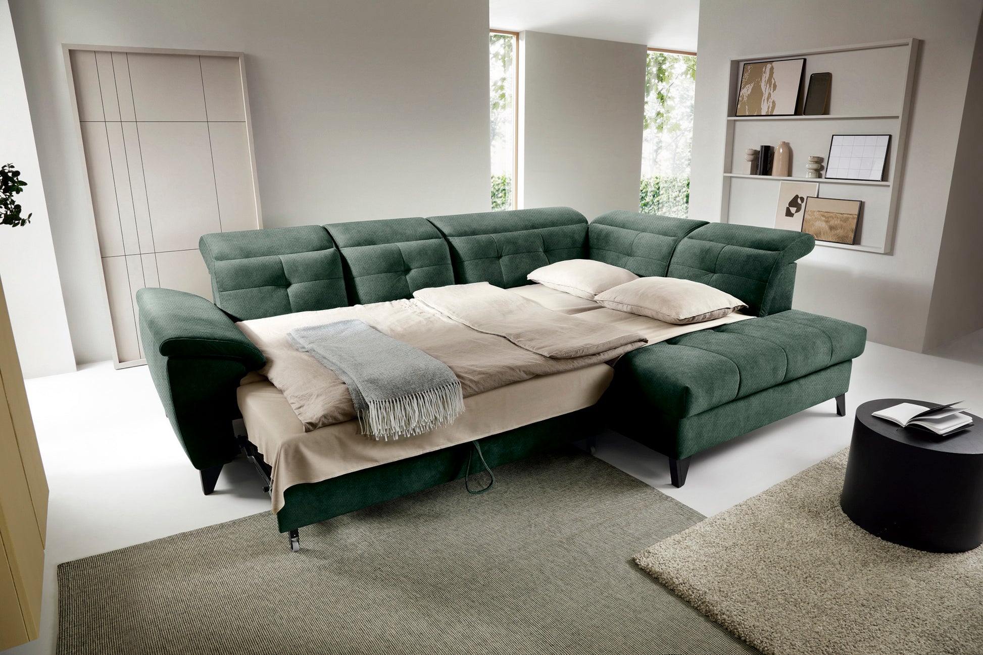 Narożnik Inferne Raquel 35 zielony w układzie prawym rozłożony jako łóżko, z pościelą i przestawionymi oparciami.