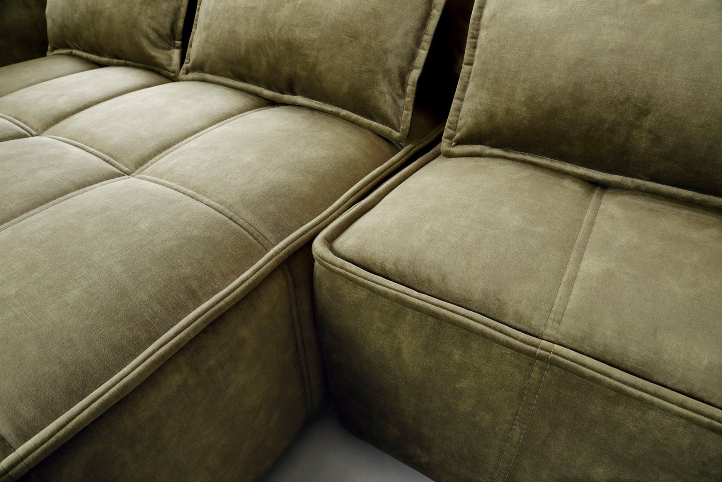 Zbliżenie pikowanego siedziska narożnika Campo Toscana 33 zielonego w układzie lewym, eksponujące równomierne przeszycia i aksamitną tkaninę.
