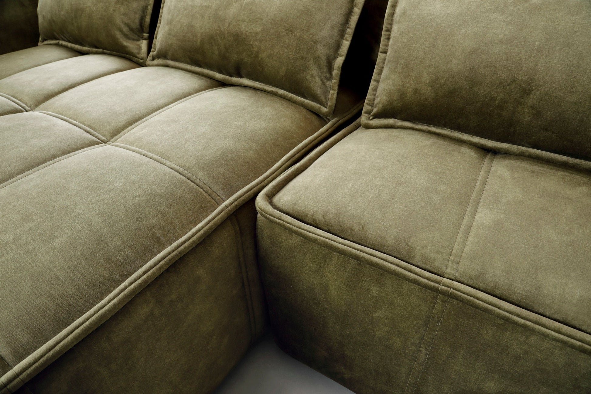 Zbliżenie pikowanego siedziska narożnika Campo Toscana 33 zielonego w układzie lewym, eksponujące równomierne przeszycia i aksamitną tkaninę.