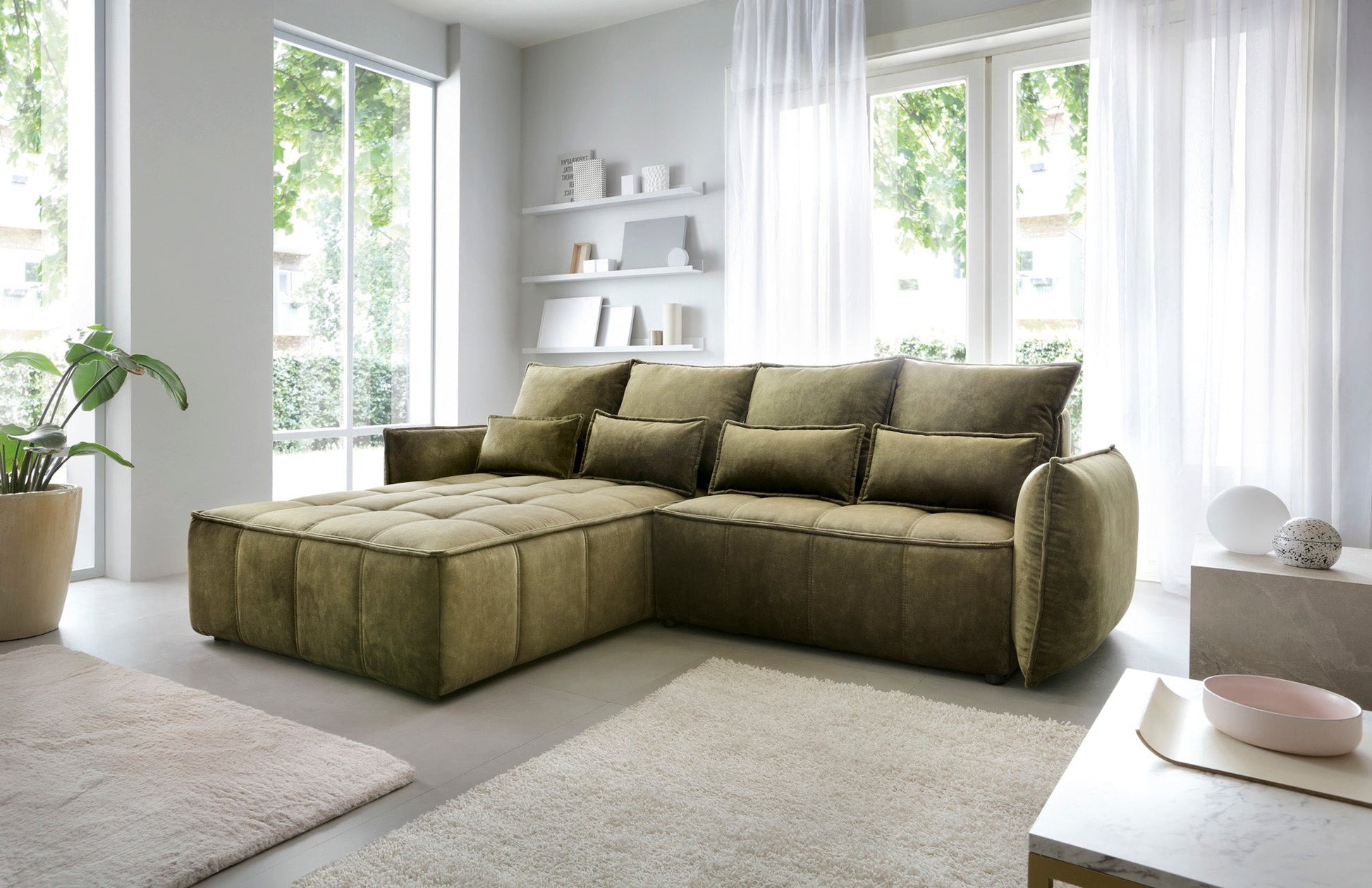 Narożnik Campo Toscana 33 zielony w układzie lewym ustawiony w eleganckiej aranżacji wnętrza z miękkim dywanem i stolikiem kawowym.