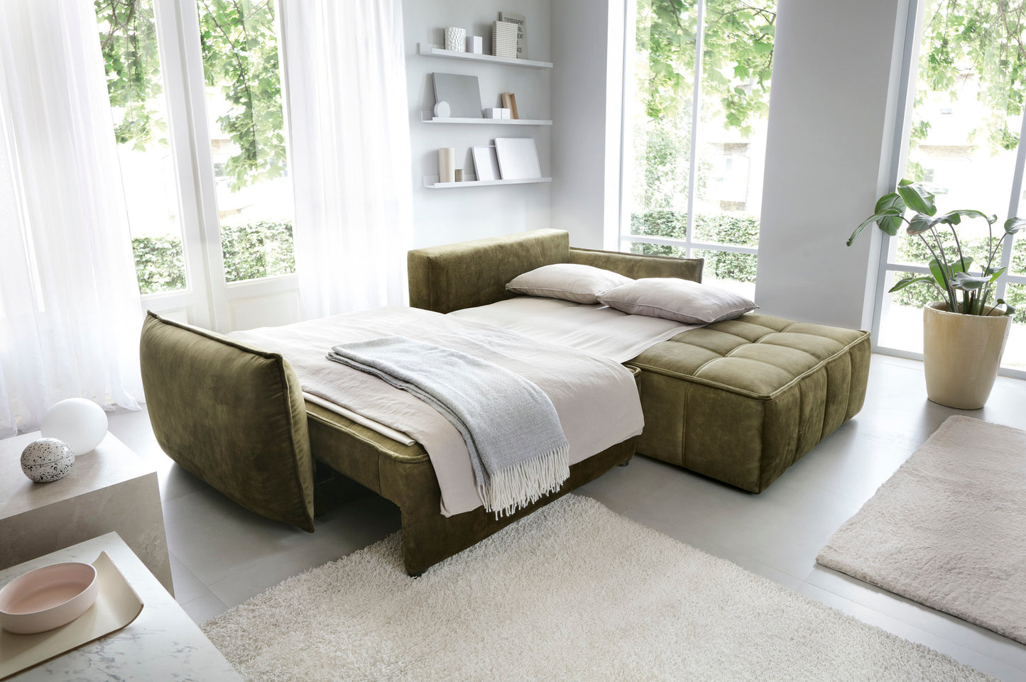 Narożnik Campo Toscana 33 zielony w układzie prawym przekształcony w funkcjonalne łóżko – rozsunięte siedzisko i nałożona pościel w pokoju dziennym.