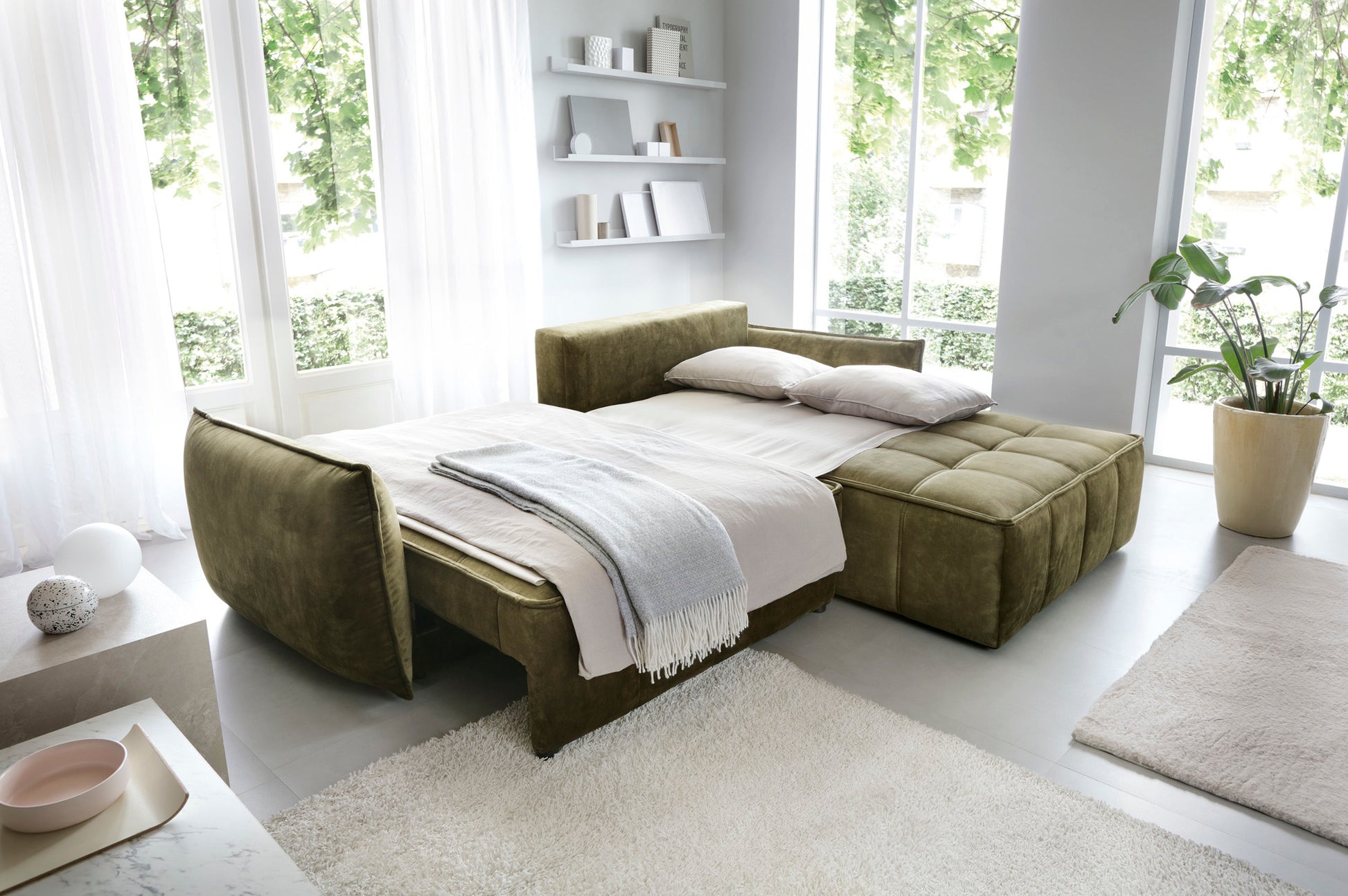 Narożnik Campo Toscana 33 zielony w układzie prawym przekształcony w funkcjonalne łóżko – rozsunięte siedzisko i nałożona pościel w pokoju dziennym.