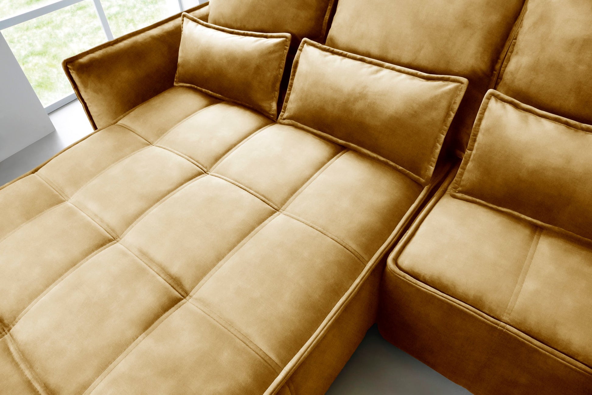 Narożnik Campo w układzie lewym, kolor Manhattan 45 żółty, rozłożony jako wygodne łóżko w przestronnym, jasnym pomieszczeniu.