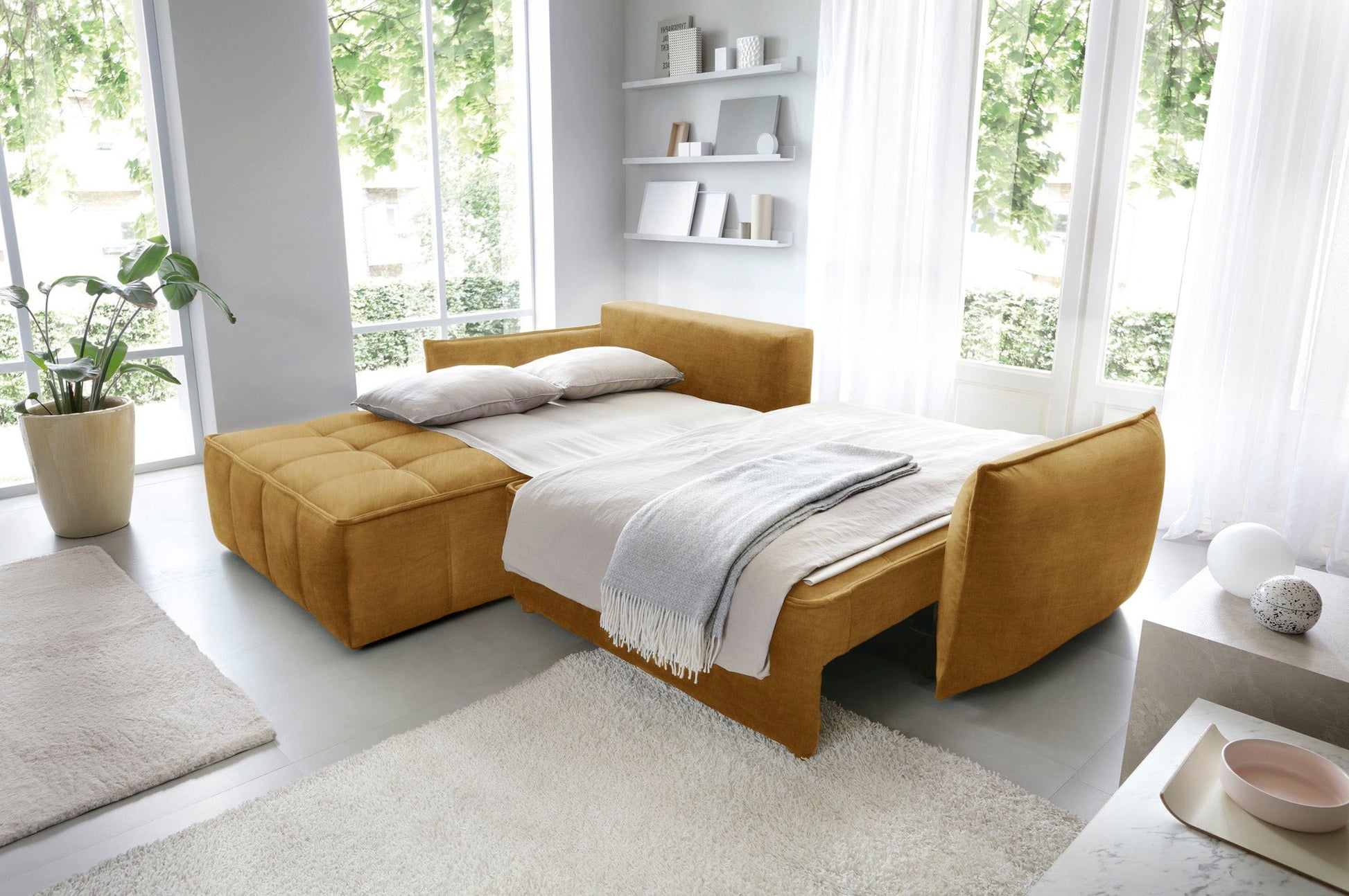 Narożnik Campo w układzie lewym, tapicerka Manhattan 45 w odcieniu żółtym, prezentowany w eleganckim salonie z dużymi przeszkleniami.