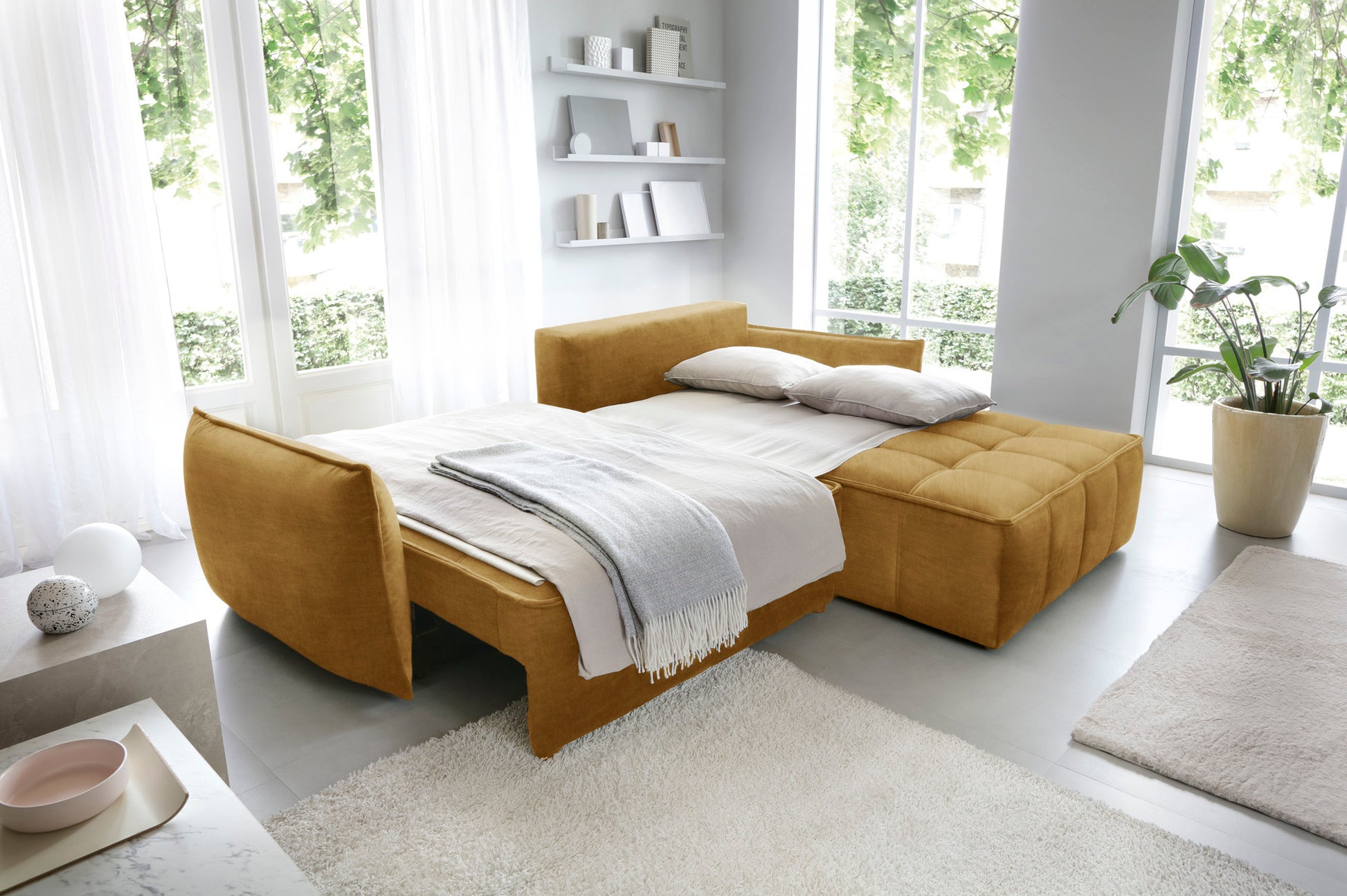 Narożnik Campo w układzie prawym, kolor Manhattan 45 żółty, rozłożony jako wygodne łóżko w przestronnym, jasnym pomieszczeniu.