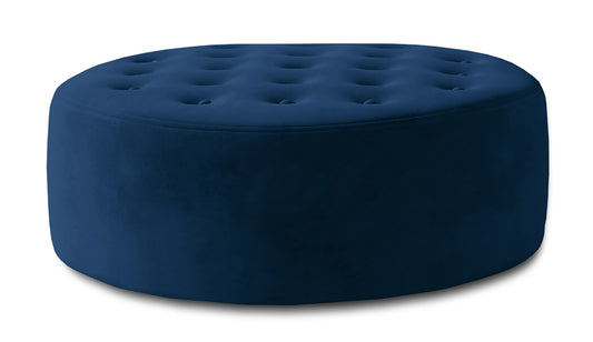 Niebieska pufa Monty w tkaninie Monolith 77 pokazana jako okrągły mebel tapicerowany z miękkim siedziskiem, dekoracyjnym pikowaniem i elegancką strukturą materiału.