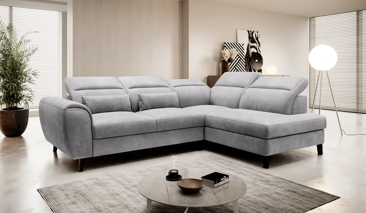 Narożnik Noble Nube 03 w subtelnym jasnoszarym kolorze prezentujący komfortowe siedziska, dekoracyjne poduszki oraz nowoczesne wykończenie tapicerki. Designerski narożnik wypoczynkowy do eleganckiego salonu i apartamentów premium.