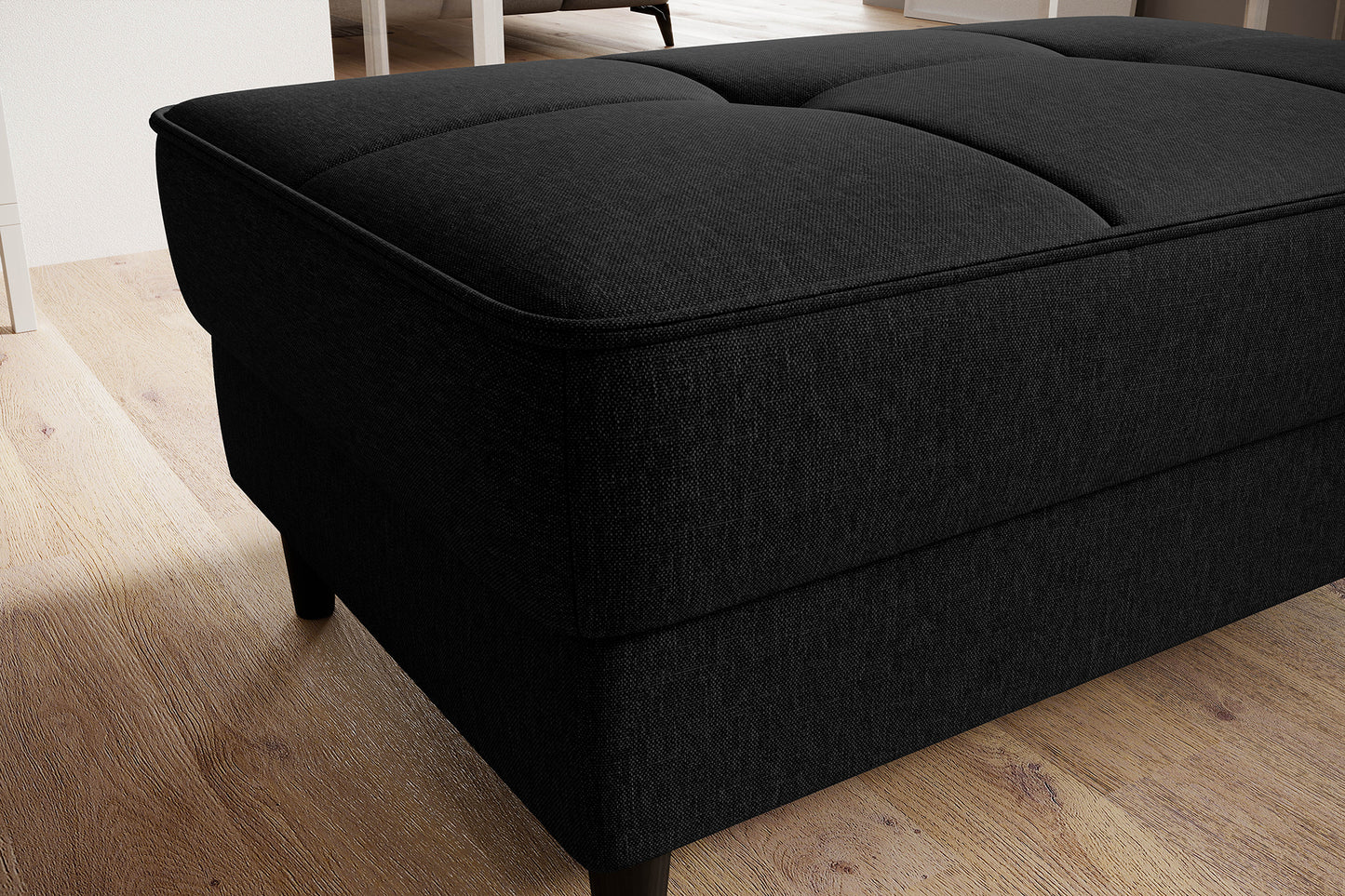 Tapicerowana pufa Bellis Flores 10 w czerni prezentuje się elegancko i bardzo uniwersalnie. Niski profil i prosta forma dobrze komponują się z wnętrzami loft i modern.