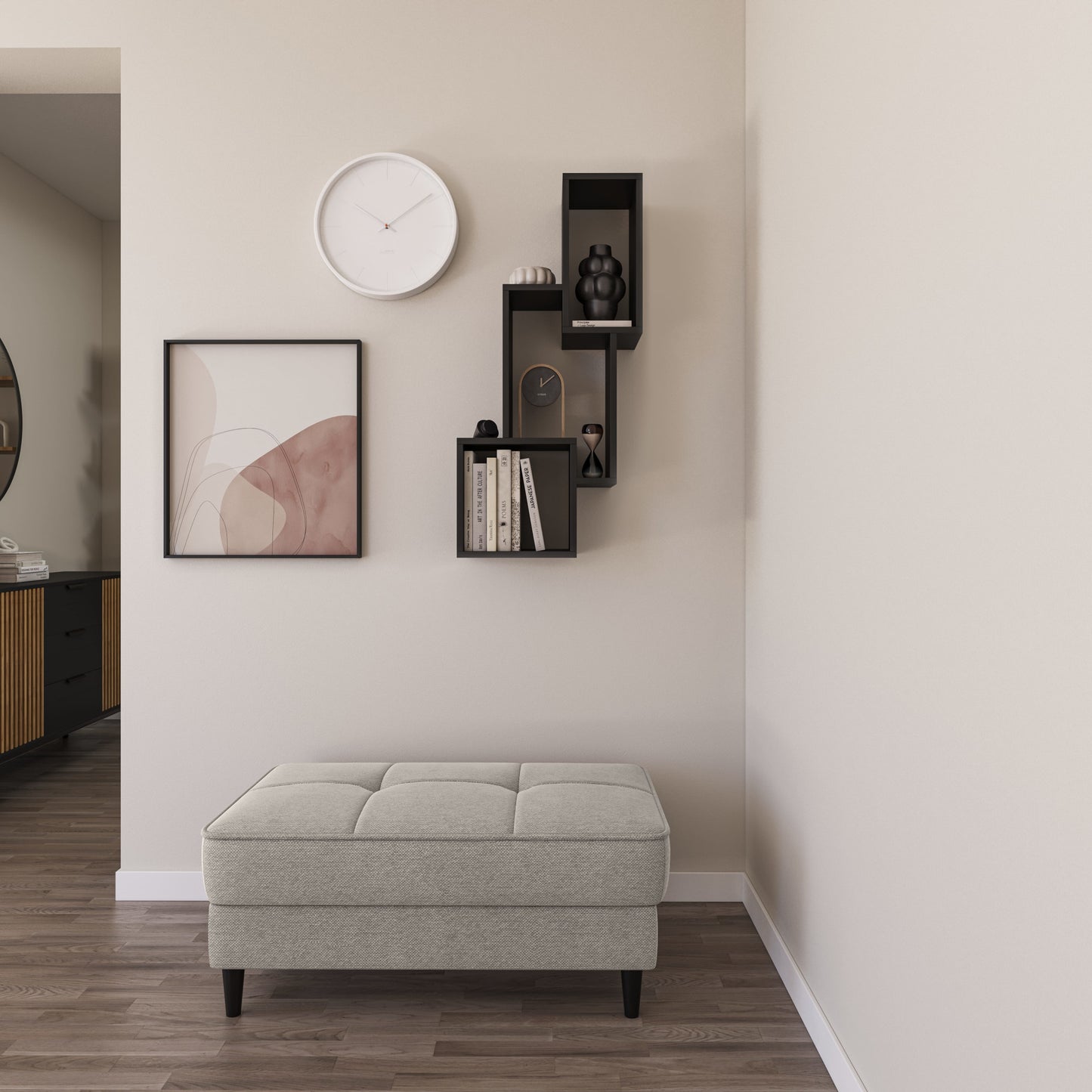 Czarna półka Alitty zamontowana na jasnobeżowej ścianie nad pikowanym pufem; na półkach stoi oprawiona grafika, biały zegar ścienny oraz kilka książek i dekoracyjnych figurek.