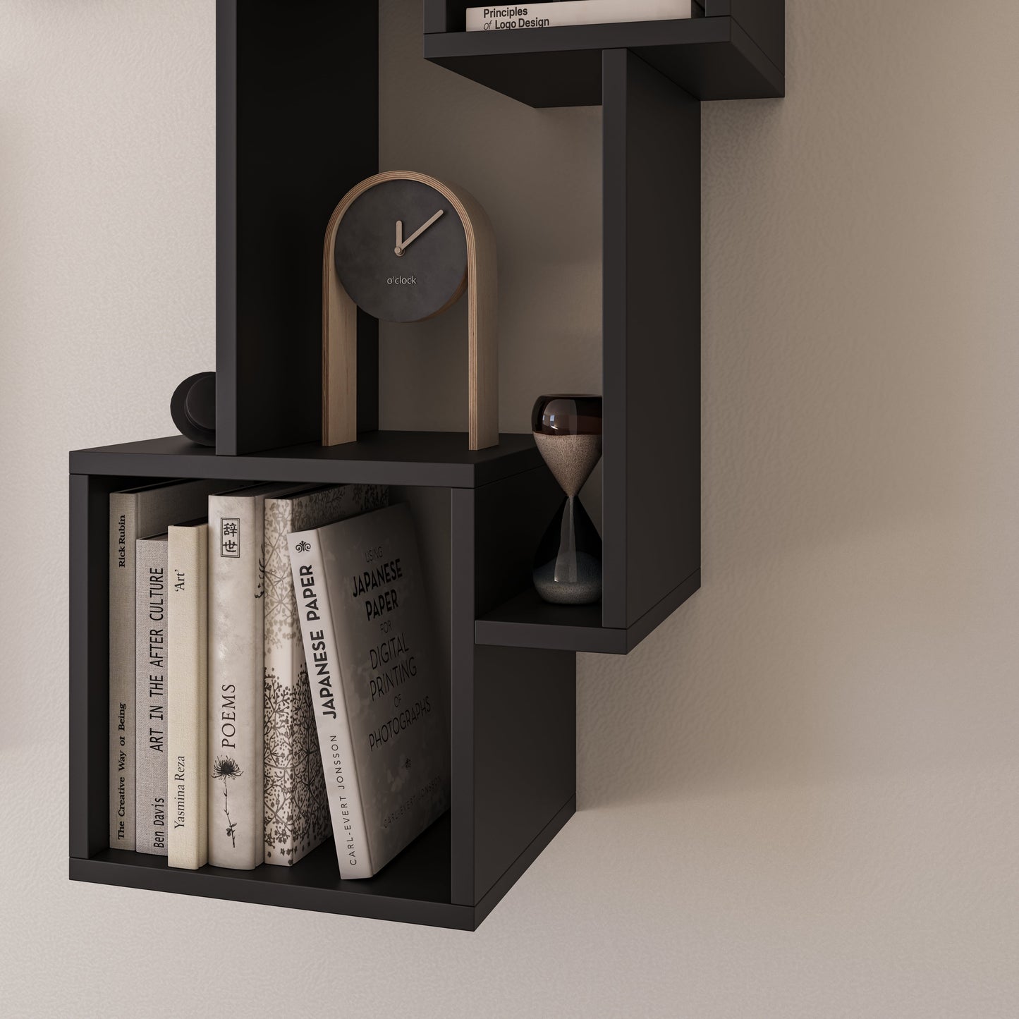 Fragment półki Alitty w czerni z kilkoma książkami, minimalistycznym zegarem na drewnianych nóżkach i szklaną klepsydrą, ustawionymi na tle neutralnej ściany.