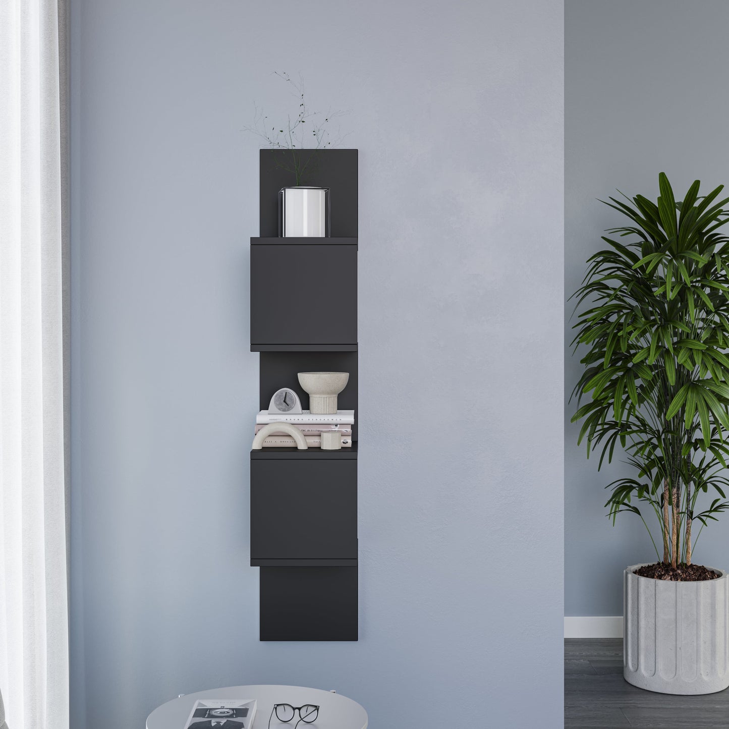 Pionowa czarna półka Sunpedo zamontowana na jasnoniebieskiej ścianie z białą doniczką na górnej półce i dekoracyjnym drzewkiem.