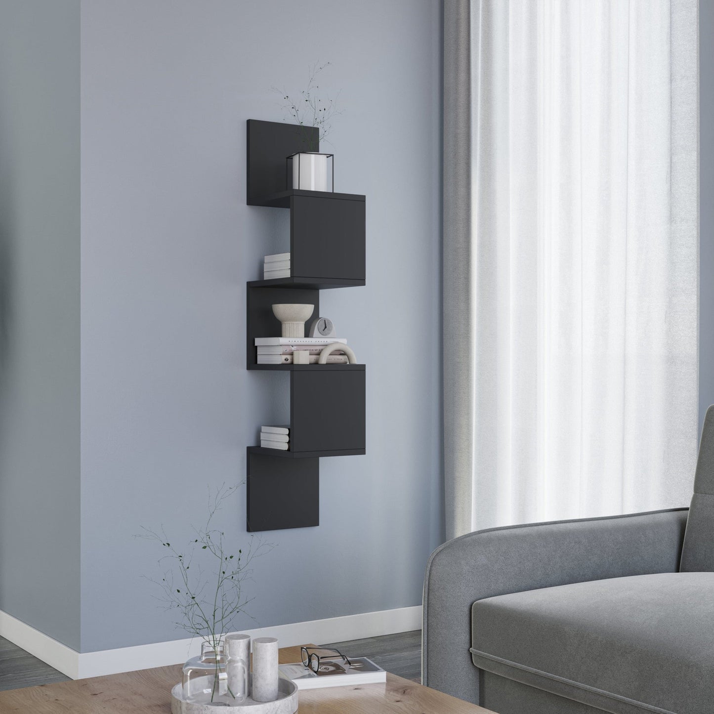 Kącik salonu z szarą sofą i niskim stolikiem kawowym, obok którego stoi pionowa czarna półka Sunpedo z otwartymi modułami na książki i ozdoby.