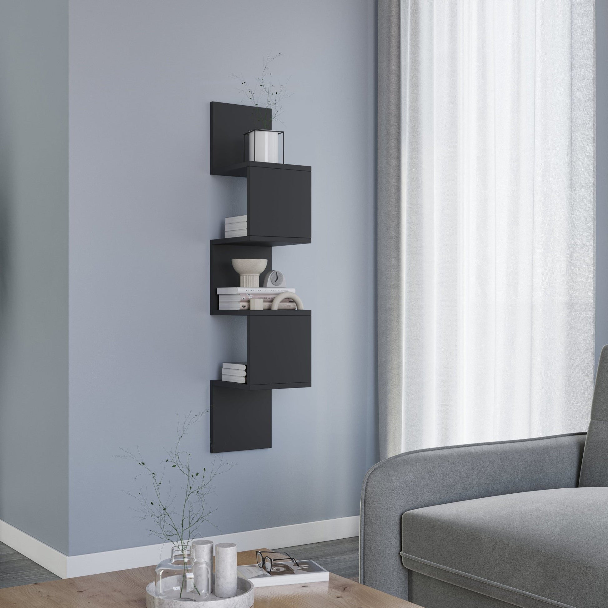 Kącik salonu z szarą sofą i niskim stolikiem kawowym, obok którego stoi pionowa czarna półka Sunpedo z otwartymi modułami na książki i ozdoby.