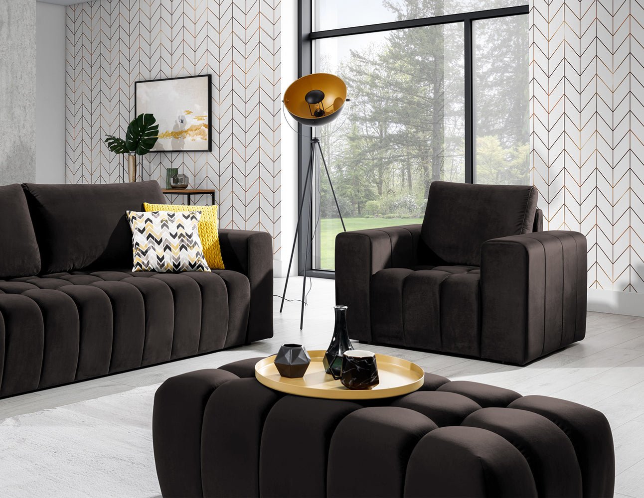 Pufa Lazaro Monolith 09 jasnobrązowa w aranżacji salonu: pufa ustawiona na środku wnętrza, przed sofą i fotelem w tym samym kolorze, na tle dekoracyjnej tapety w jodełkę, obok lampy na trójnogu i stolika kawowego z tacą.