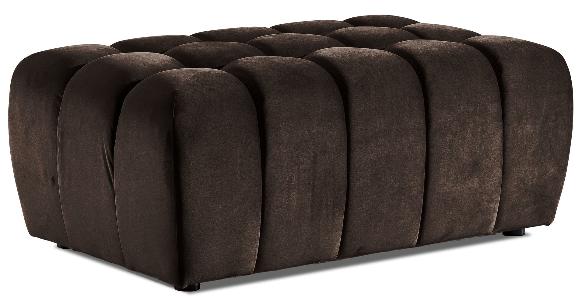 Pufa Lazaro Monolith 09 jasnobrązowa, widok 3/4: niska, prostokątna pufa obita aksamitnym materiałem w ciepłym odcieniu jasnobrązowym, z charakterystycznym pikowaniem w zaokrąglone, pionowe pasy.