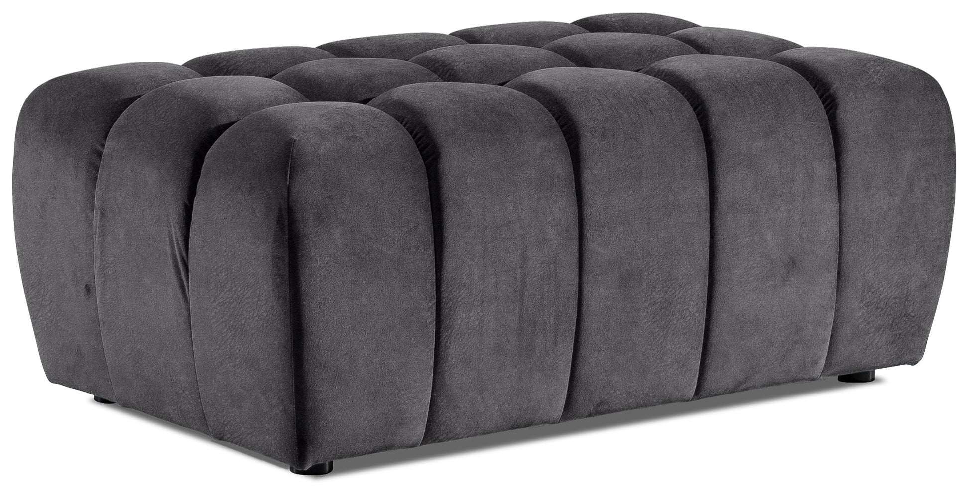 Prostokątna pufa Lazaro obita miękkim welurem w ciemnoszarym odcieniu Monolith 09, z charakterystycznymi, zaokrąglonymi pionowymi przetłoczeniami, ukazana z przodu na białym tle.