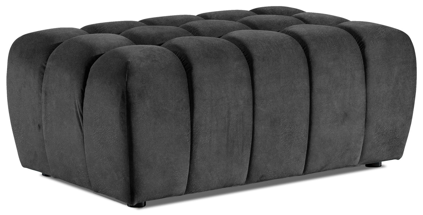 Prostokątna pufa Lazaro obita miękkim welurem w głębokim czarnym odcieniu Dora 96, z charakterystycznymi, pionowymi, zaokrąglonymi przetłoczeniami, sfotografowana na czystym białym tle.