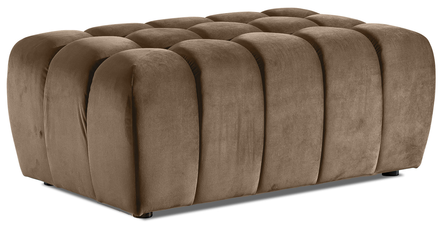 Pufa Lazaro Monolith 09 jasnobrązowa, widok 3/4: niska, prostokątna pufa obita aksamitnym materiałem w ciepłym odcieniu jasnobrązowym, z charakterystycznym pikowaniem w zaokrąglone, pionowe pasy.