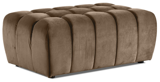 Pufa Lazaro Monolith 09 jasnobrązowa, widok 3/4: niska, prostokątna pufa obita aksamitnym materiałem w ciepłym odcieniu jasnobrązowym, z charakterystycznym pikowaniem w zaokrąglone, pionowe pasy.