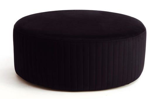 Pufa Lara w kolorze Mat Velvet 99 czarny, okrągła, tapicerowana welurem z pionowym przeszyciem po bokach, prezentowana na białym tle.